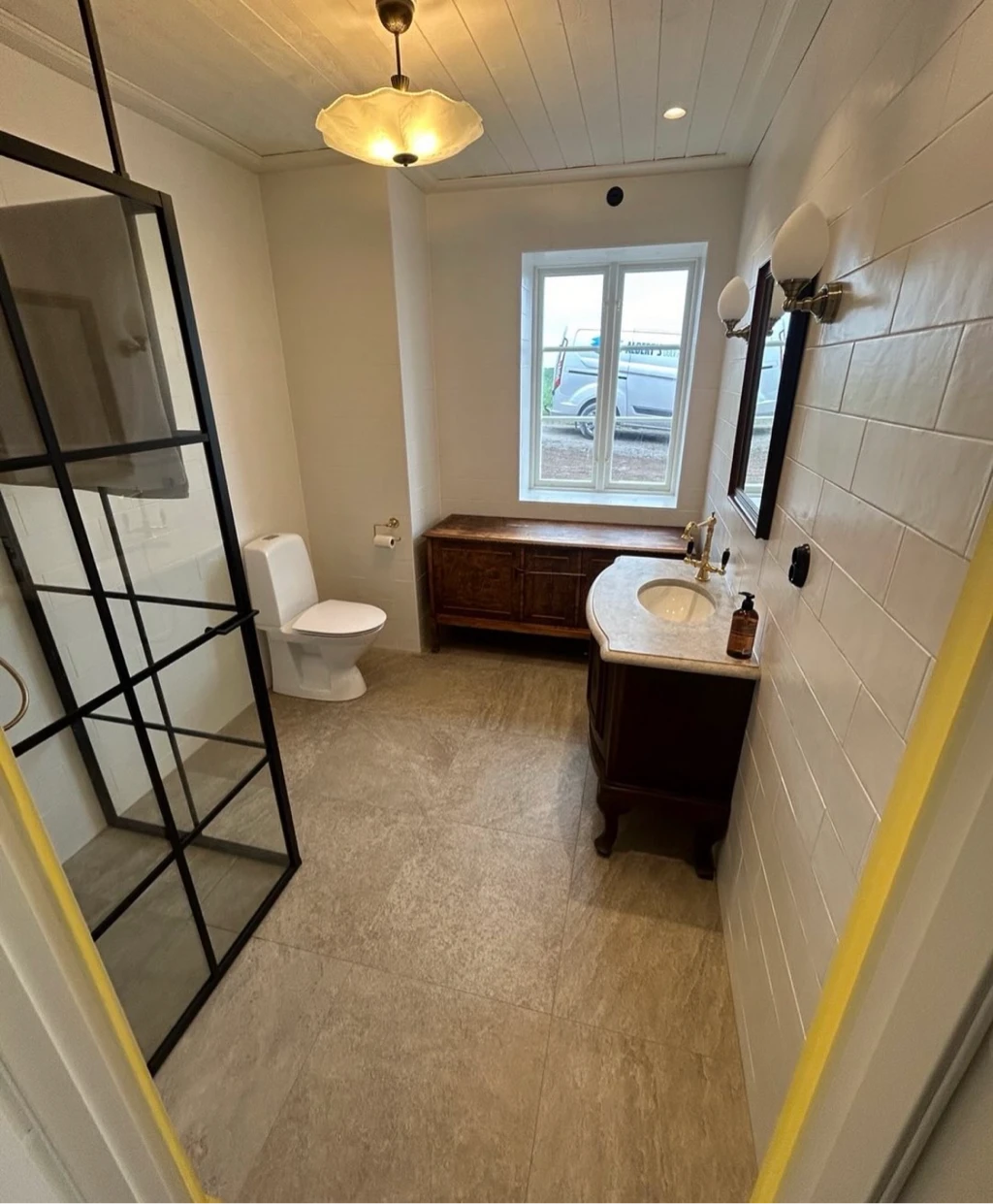 Badrum med klinker och stålduschvägg